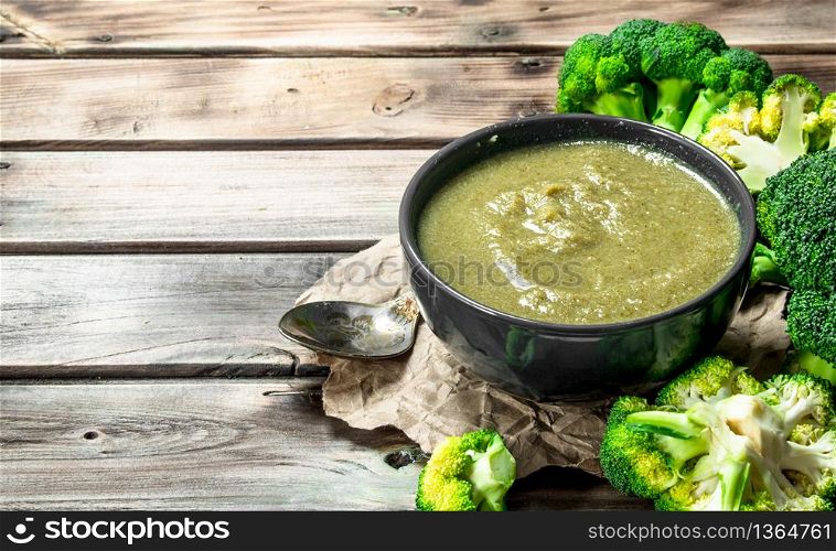 Puree broccoli in a bowl with a spoon. On a wooden background.. Puree broccoli in a bowl with a spoon.