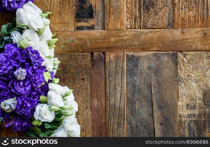 Purple and white contrasting flowers placed on wooden surface.