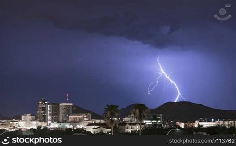 Purple Blue light illuminates the sky over the buildings homes and hills around Tucson Arizona