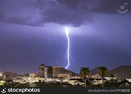 Purple Blue light illuminates the sky over the buildings homes and hills around Tucson Arizona