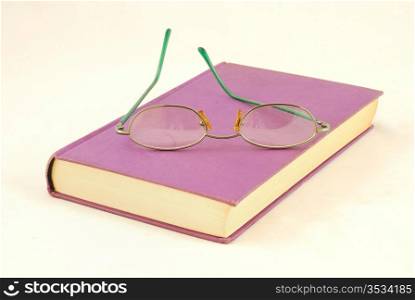 Purple book and green glasses on white background culture and leisure suggests
