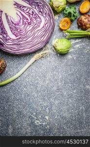 Purple cabbage and vegetables ingredients for cooking on gray rustic background, top view. Vegetarian and health food concept. Border