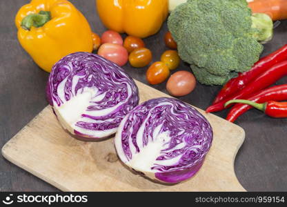 Purple cabbage on cutting board with various vegetables on wooden background,Food background,Healthy concept