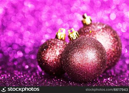 Purple christmas balls over shiny glitter background
