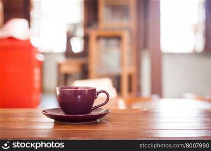Purple coffee cup on wooden table in coffee shop