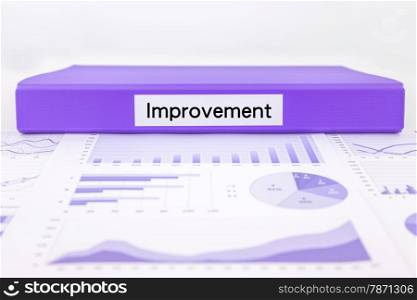 Purple document binder with Improvement word place on assessment document, graph analysis and education reports
