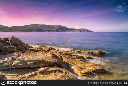 Purple evening sky over La Revellata lighthouse with rocks and sea in the foreground near Calvi in Corsica