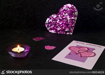 Purple heart, a burning candle and card on February 14, Valentine’s Day on a black background. Valentines day greeting card.. Purple heart, a burning candle and card on February 14, Valentine’s Day on a black background. Valentines day greeting card