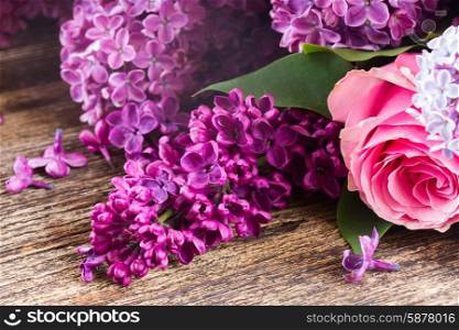 Purple Lilac flowers with pink roses on wooden table close up . Lilac flowers