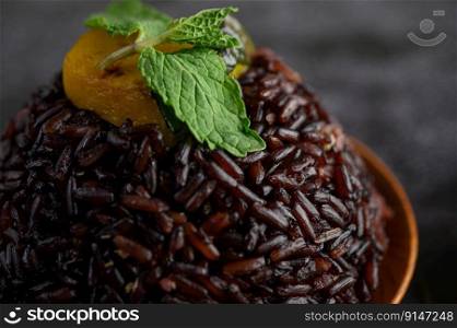 Purple rice berries cooked in a wooden dish with mint leaves and pumpkin. Selective focus