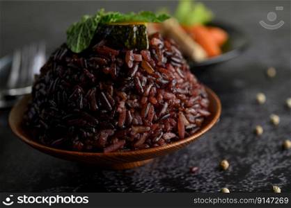Purple rice berries cooked in a wooden dish with mint leaves. Selective focus