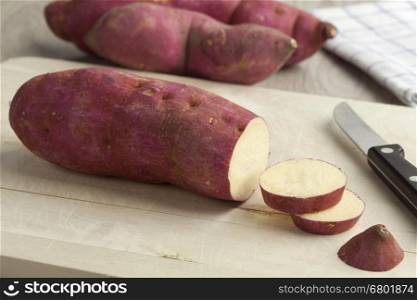 Purple sweet potatoes with slices on a cutting board