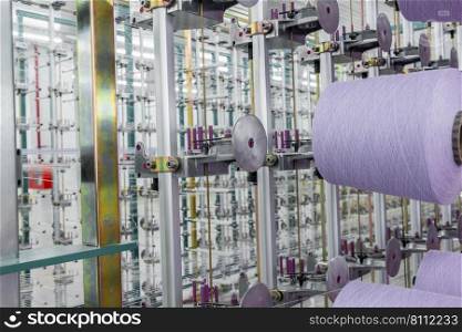 purple textile yarn on the warping machine. machinery and equipment in a textile factory. textile yarn processing shop