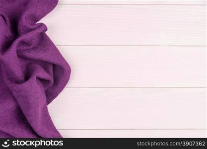 Purple towel over wooden kitchen table. View from above.