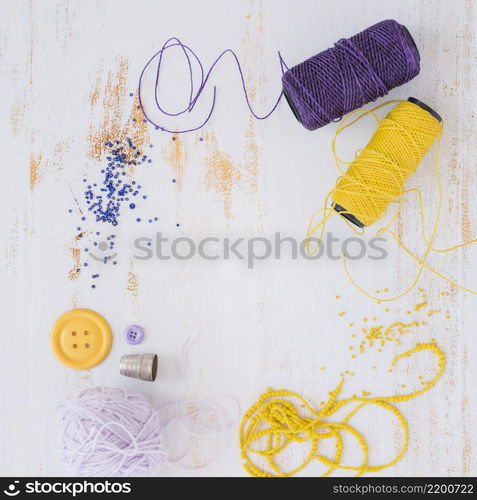 purple yellow yarn ball button with beads white wooden textured backdrop