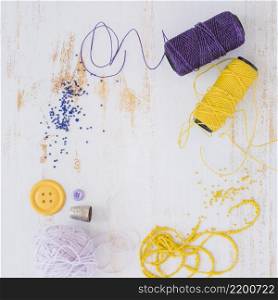 purple yellow yarn ball button with beads white wooden textured backdrop
