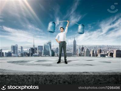 Purposeful and confident businessman raises a bar of bottles with water, cityscape on background. Succuss business concept