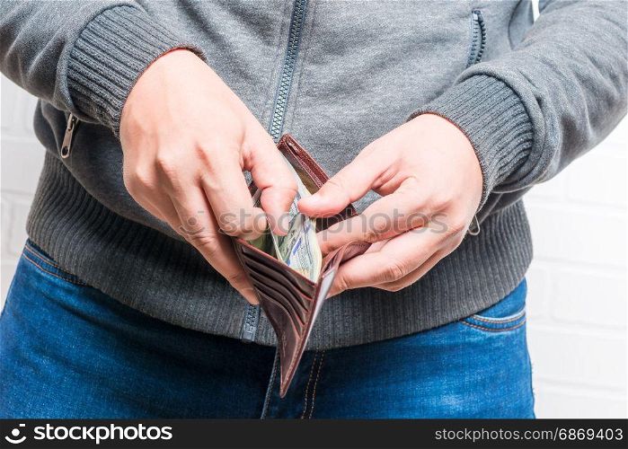 Purse stuffed with dollars in men&rsquo;s hands closeup