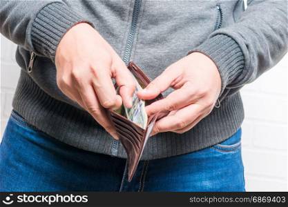 Purse stuffed with dollars in men&rsquo;s hands closeup