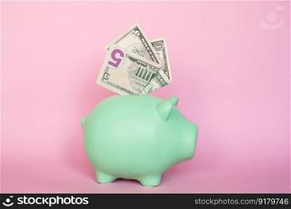 Put the bills in the piggy bank. 5 and 1 dollar bills on a pink background in a piggy bank