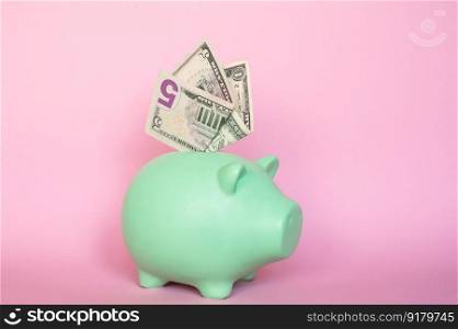 Put the bills in the piggy bank. 5 and 10 dollar bills on a pink background in a piggy bank