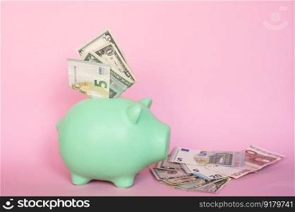 Put the bills in the piggy bank. Banknotes of 5 and 10 euros and dollars on a pink background in a piggy bank