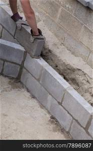 Putting bricks on a constructed wall outdoors