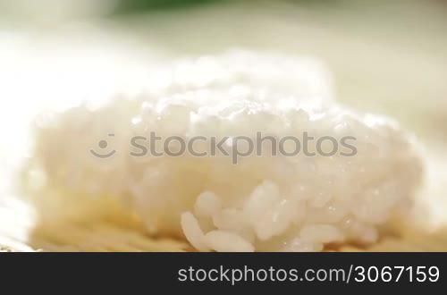 Putting piece of salmon on the rice. Cooking sushi roll. Beautiful backlight macro.