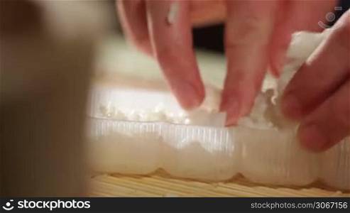 Putting rice in a plastic shape. Cooking sushi rolls.