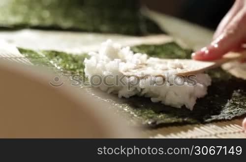Putting rice on nori. Making sushi rolls.