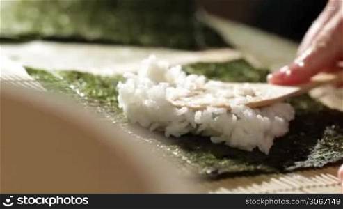 Putting rice on nori. Making sushi rolls.