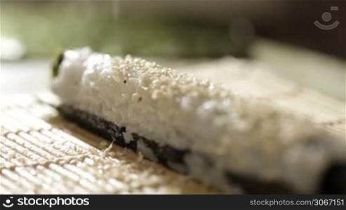 Putting sesame on sushi roll.