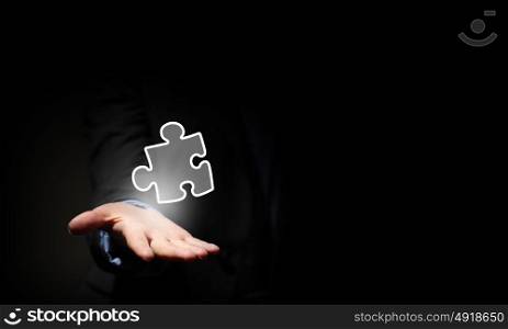 Puzzle element. Close up of businessman&rsquo;s hand holding puzzle piece