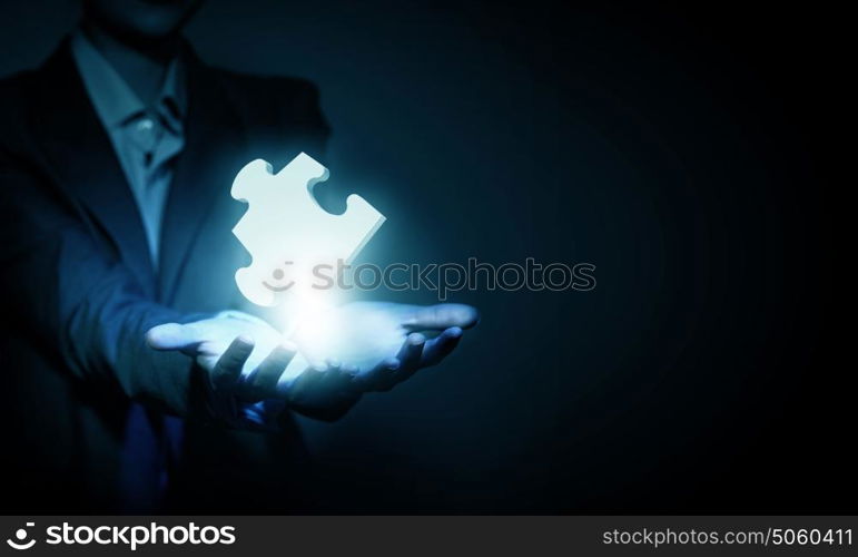 Puzzle element. Close up of businessman&rsquo;s hand holding puzzle piece