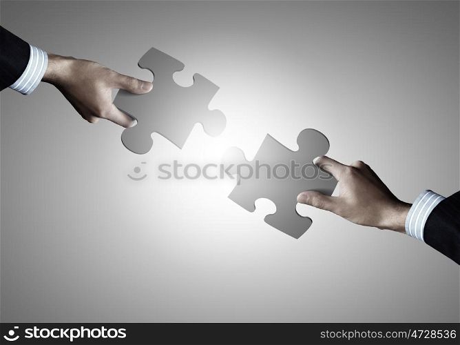 Puzzle game. Close up of human hands connecting puzzle elements