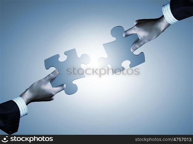 Puzzle game. Close up of human hands connecting puzzle elements