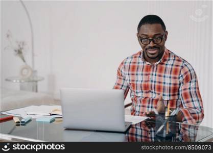 Puzzled african american man reading email working at laptop. Perplexed black male manager looking at computer screen. Broken or discharged device, poor internet connection. Problem at remote work.. Puzzled african american man look at laptop screen. Poor internet connection. Problem at remote work