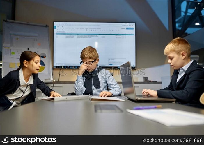 Puzzled boss and employee team in meeting room. Children business partners discuss problem. Boss and employee team in meeting room