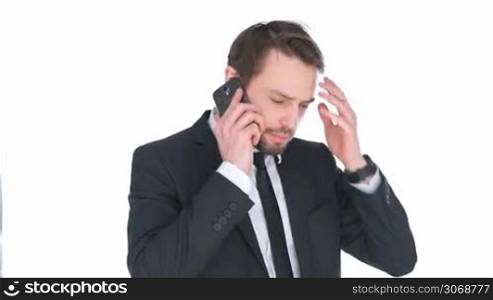 Puzzled businessman talking on a mobile phone scratching his head in confusion, isolated on white