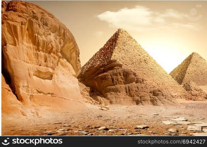 Pyramid in sand dust under yellow clouds