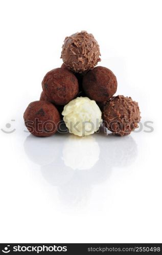 Pyramid of assorted chocolate truffles on white background with reflection
