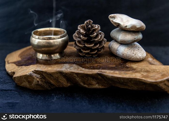 Pyramid of zen stones, Pine cones and Burning candle on old wooden background, Meditation concept, dark toned style. Zen background