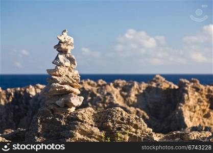 Pyramid shaped stack of rocks balanced on the edge of ocean