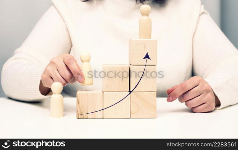 pyramids from wooden cubes and figurines of men on the table. The concept of achieving goals, moving up the career ladder. Detection of single-minded personality