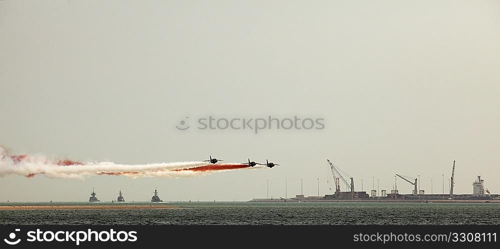 Qatari warplanes trailing national colours of white and maroon fly low past Doha Port, while three Qatari warships head out into the Gulf as part of Qatar National Day celebrations, December 2009