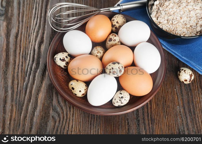 Quail and chicken eggs in a clay plate on a wooden background