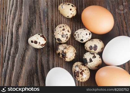 Quail and chicken eggs on a wooden background. White and brown chicken eggs.