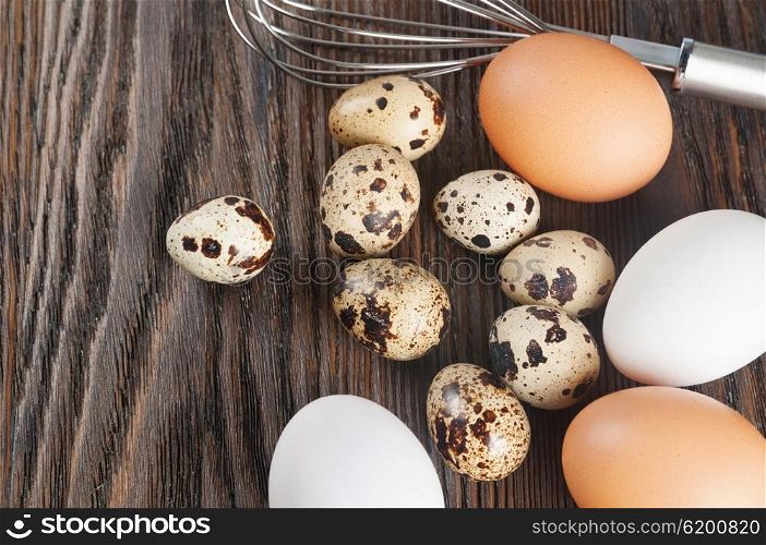 Quail and chicken eggs on a wooden background. White and brown chicken eggs.