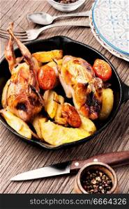 Quail baked with a garnish of potatoes in pan. Roasted quail with vegetable