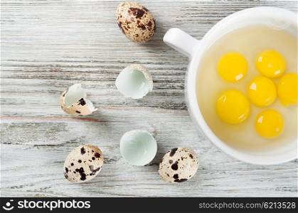 Quail egg yolks in a white plate on a wooden background. Top view.